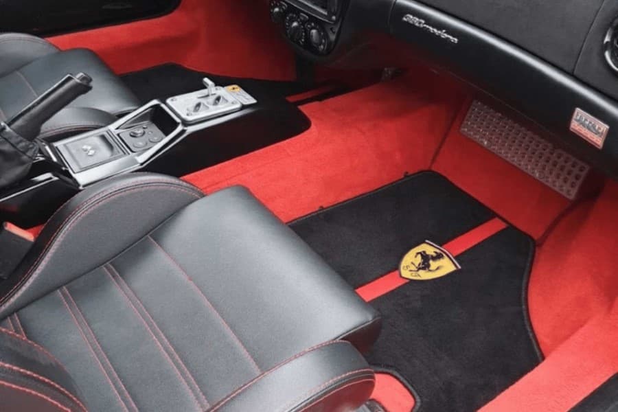 Ferrari-Innenraum mit schwarzen Ledersitzen und roten Fußmatten